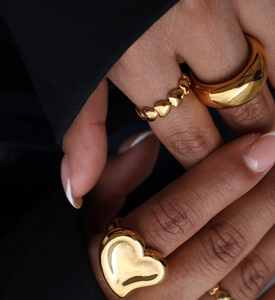 Close-up of a stacked gold heart ring set worn on finger with minimalist design