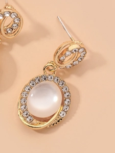 Gros plan détaillé de boucles d'oreilles dorées avec pierres œil-de-chat et pavé de cristaux