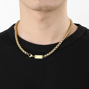 Gros plan d'un collier chaîne box dorée en acier inoxydable avec pendentif rectangulaire
