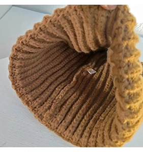 Détail du bonnet en tricot camel foncé avec texture douce et étiquette de soin interne