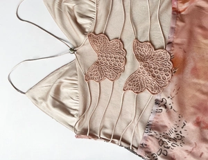 Detail of butterfly lace embroidery and strappy cutout design on champagne mesh dress