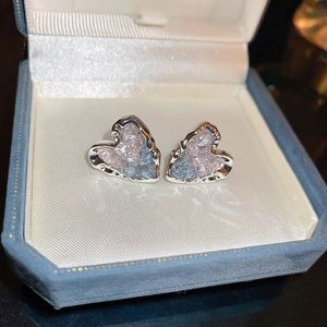 Macro view of heart-shaped silver earrings with pink and blue crystals in a jewelry box