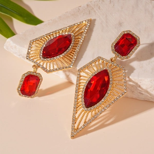 Detail view of vintage gold earrings with geometric red gems and sparkling rhinestones