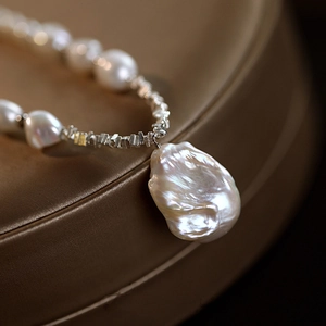 Macro shot of an irregular baroque pearl pendant on a minimalist beaded necklace