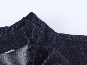 Detailed view of dark blue denim shirt collar featuring elegant ruffled edges and textures