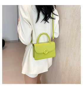 Detail view of grass green small square PU bag with gold hardware worn by a model