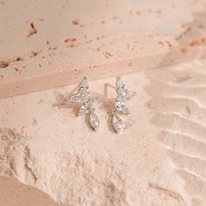 Macro view of silver leaf studs with clear marquise-cut zircons on a natural stone surface