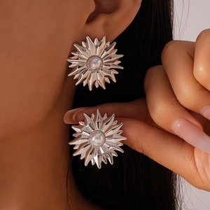 Detailed view of silver sunflower stud earrings with a pearl center on a model