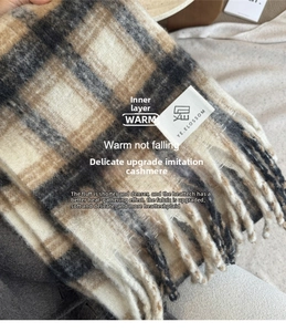 Detail shot of cashmere-like plaid scarf with brand label and soft fringe tassels