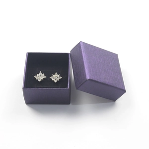 Close-up of sparkling diamond stud earrings inside a textured purple jewelry gift box
