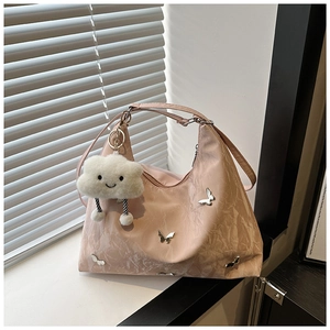 Pink pleated tote bag detail with silver butterfly charms and white cloud keychain