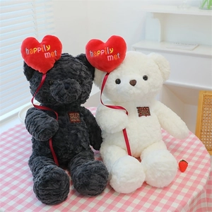 Detail of black and white teddy bears holding red plush hearts with embroidered text