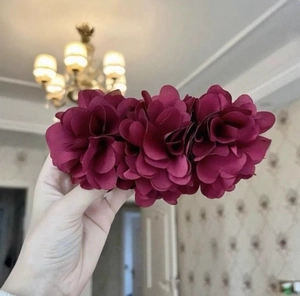 Detail view of large burgundy fabric flower banana clip held in hand with layered petals