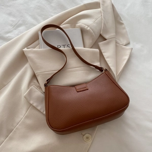 Close-up of brown lychee-patterned leather texture and zipper detail on shoulder bag