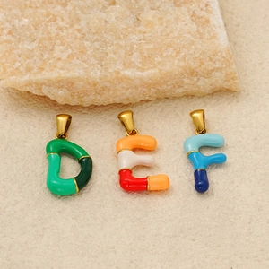 Colorful enamel letter pendants D E F in gold titanium steel on a beige textured background