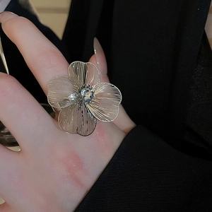 Macro detail of oversized silver hollow flower ring with crystal center on model