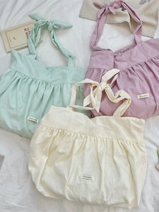Flat lay of pleated canvas tote bags with bow straps in pastel green pink and yellow