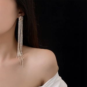 Macro shot of silver tassel earrings with sparkling rhinestones worn on a model