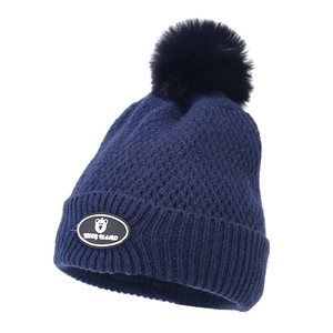 Close-up of navy blue knitted beanie with fluffy pom-pom and Teddy Island bear patch