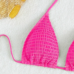 Detailed close-up of hot pink smocked bikini top with halter ties and summer accessories