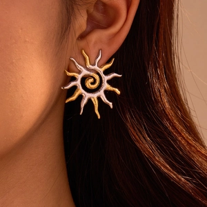 Two-tone stainless steel sun flame earrings with a spiral center on model ear