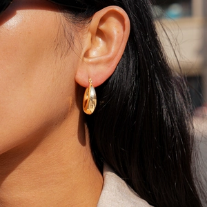 Close-up of model wearing chunky gold water-drop earrings with mirror polish finish