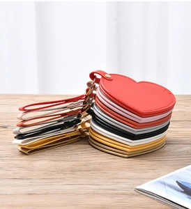 Close-up of heart-shaped leather keychain mirrors in various colors on wooden surface