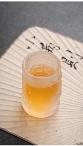 Detailed relief of a frosted glass tea cup with a cat motif on a traditional fan background