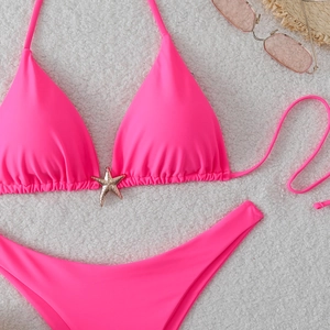 Flat lay of pink neon bikini with starfish metal charm on a white wool texture background