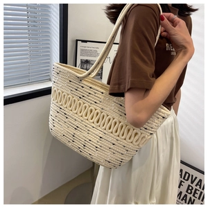 Detailed view of beige woven tote bag with 3D wave texture on a female model shoulder