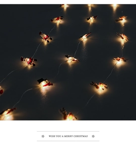 Detail of warm LED Christmas string lights with Santa and reindeer hanging ornaments