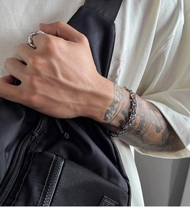 Detailed view of silver titanium steel hip hop chain bracelet and ring on male wrist