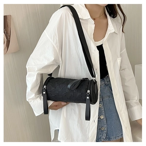Detailed view of black cylinder bag with 3D texture and wide shoulder strap