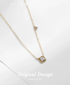 Detail of a square zircon pendant on a gold chain with elegant lighting and shadows