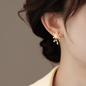Elegant gold snowflake stud earrings with white pearl and sparkling zircon on model