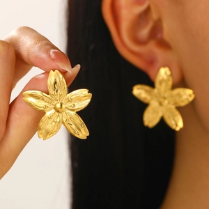 Elegante goldene Blumenohrringe mit Knitterstruktur, getragen von einem Model im Studio
