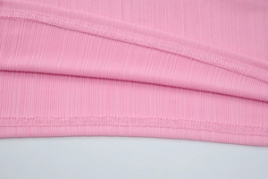 Vista macro del tessuto a coste rosa con trama elastica e dettaglio dell'orlo a doppia cucitura