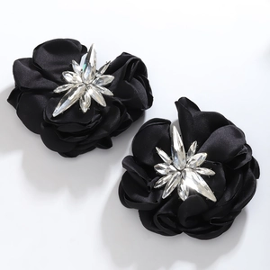 Close-up of black satin camellia flower earrings with a sparkling rhinestone center