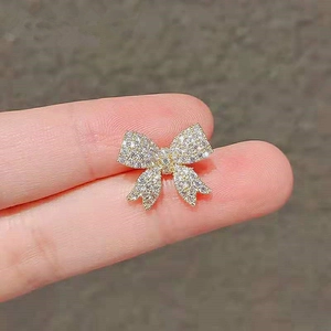 Close-up of a small gold bow-shaped brooch with white cubic zirconia pavé setting