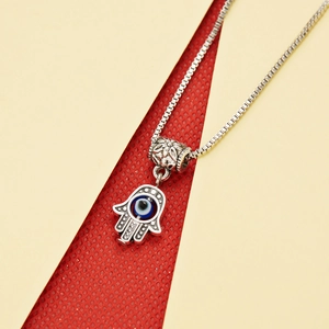 Detail of silver Hamsa Hand necklace with blue Evil Eye charm on a box chain