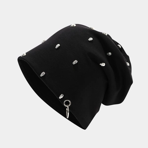 Detail of black knitted beanie featuring silver skull studs and a metal ring pendant