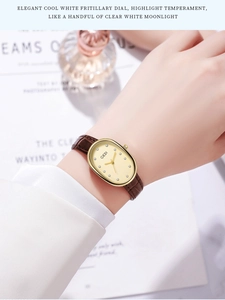 Detail of elegant oval gold watch with pearl dial and brown leather strap on wrist