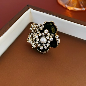 Close-up of vintage flower jewelry with black enamel, sparkling crystals, and a center pearl