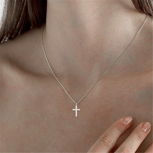 Detail close-up of a classic S925 sterling silver cross necklace worn by a female model