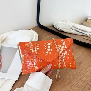 Orange envelope crossbody bag with gold crocodile pattern and fine metal chain strap