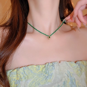 Close-up of a delicate green beaded necklace with a gold diamond-encrusted pendant