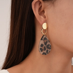 Close-up of vintage leopard print teardrop earrings with golden metal accents on model
