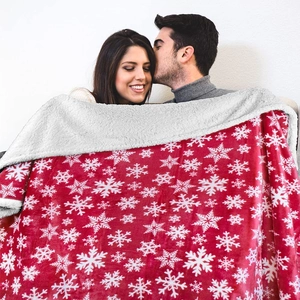 Christmas sherpa fleece blanket with red snowflake pattern shown on a cozy couple
