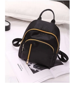 Close-up of black waterproof nylon mini backpack with gold zippers and leather handle