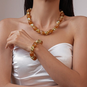 Detailed shot of amber resin and gold geometric beads on necklace and bracelet set